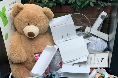 A large teddy bear and other waste items dumped on a floor