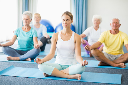 An indoor yoga class with  a group of people sitting on yoga mats