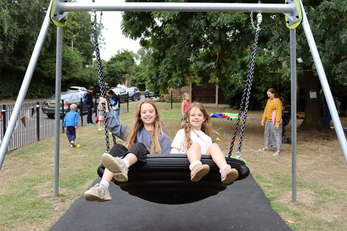 Two children playing on a new swing installed at a play area in Gamston